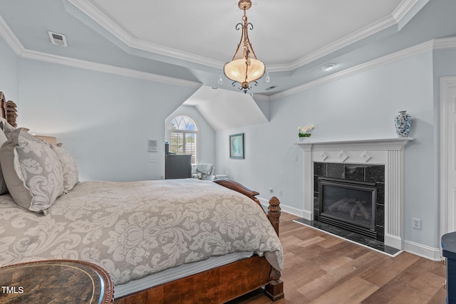 bedroom with wood finished floors, ornamental molding, a fireplace, and baseboards