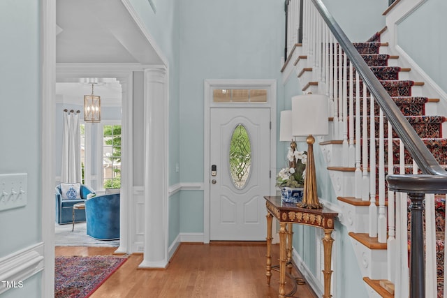 entryway with stairway, wood finished floors, crown molding, and baseboards