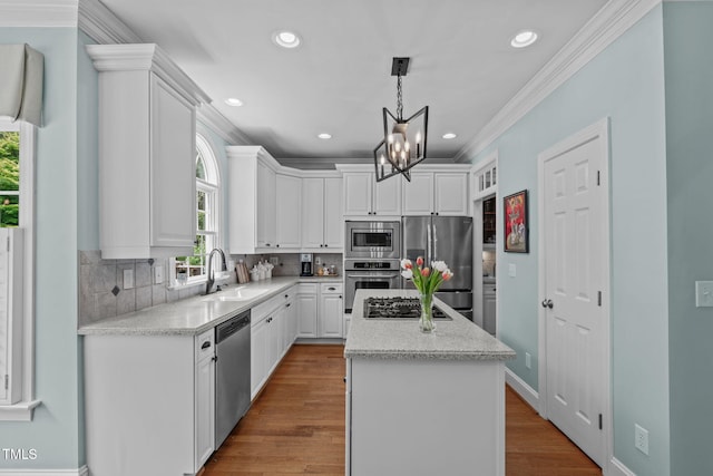 kitchen with stainless steel appliances, a sink, a kitchen island, a chandelier, and white cabinets