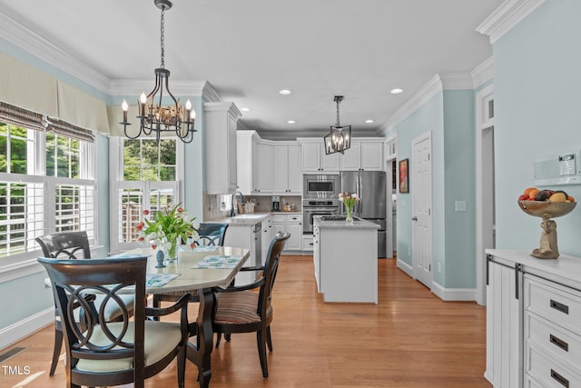 dining space featuring a chandelier, ornamental molding, plenty of natural light, baseboards, and light wood-type flooring