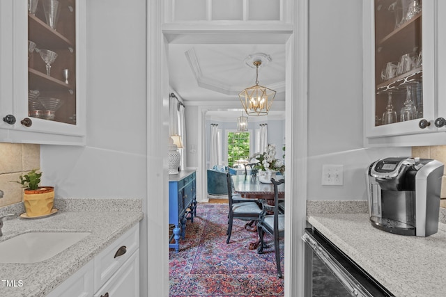 bar featuring crown molding, a chandelier, decorative backsplash, a sink, and decorative light fixtures