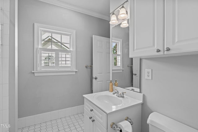 bathroom with toilet, healthy amount of natural light, vanity, and ornamental molding