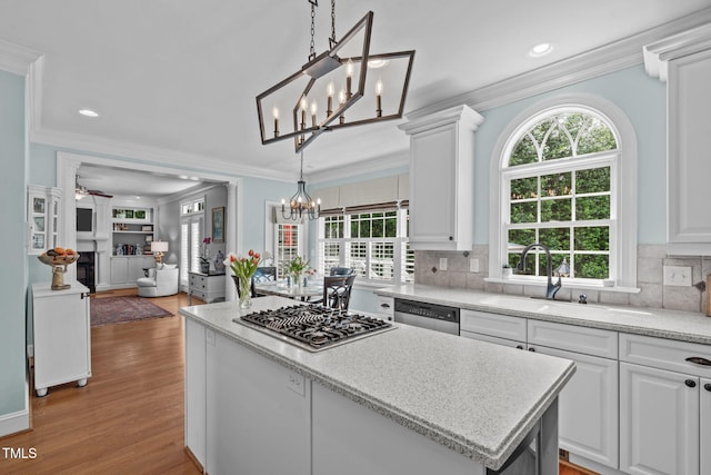 kitchen featuring a chandelier, stainless steel appliances, ornamental molding, white cabinets, and wood finished floors