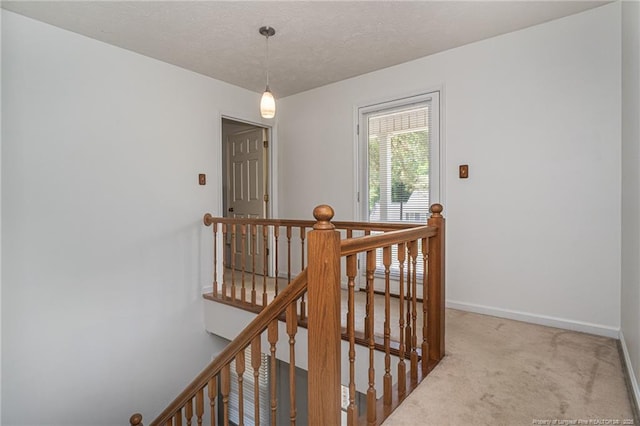 corridor with carpet floors, baseboards, and an upstairs landing