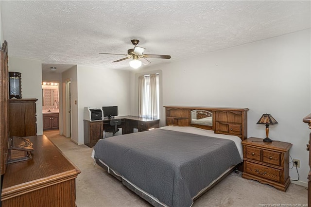 bedroom featuring ceiling fan, light carpet, a textured ceiling, and ensuite bath