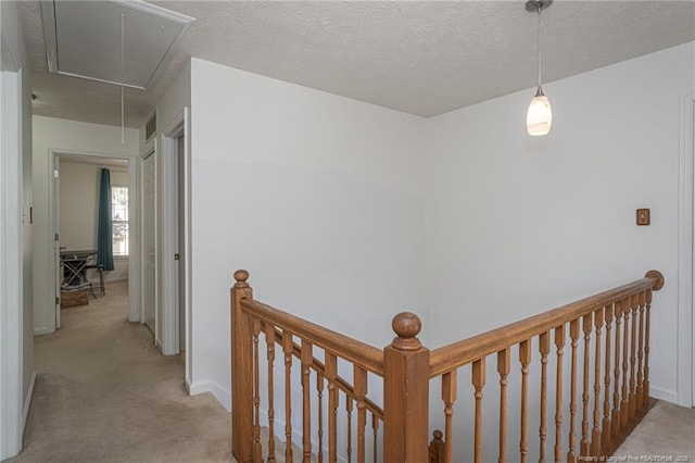 hallway featuring attic access, carpet, baseboards, visible vents, and an upstairs landing