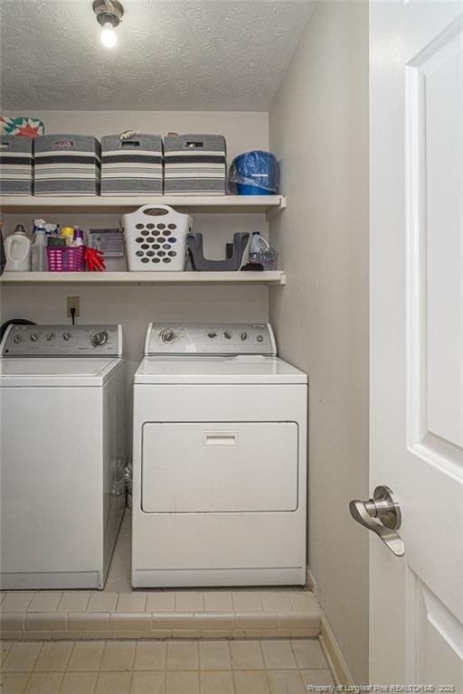 washroom featuring laundry area, a textured ceiling, separate washer and dryer, and light tile patterned floors