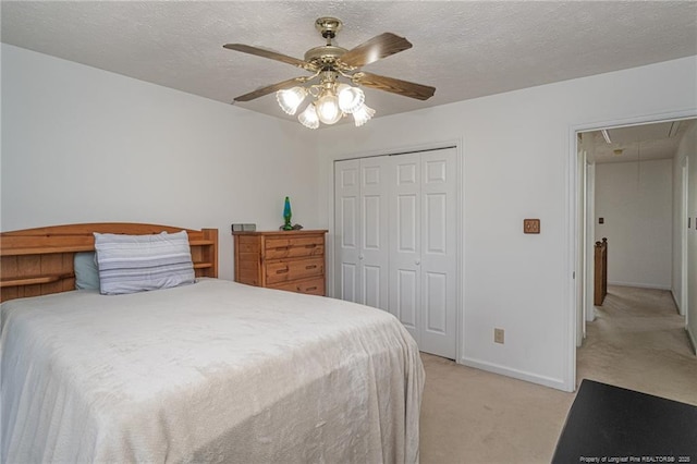 bedroom with a closet, attic access, a textured ceiling, baseboards, and light colored carpet