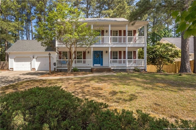 view of front of property featuring covered porch, fence, a balcony, a garage, and a front yard