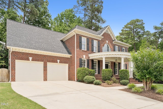 325 Wescott Ridge Dr, Holly Springs, NC 27540 - colonial-style house with brick siding, a porch, a garage, a shingled roof, and concrete driveway
