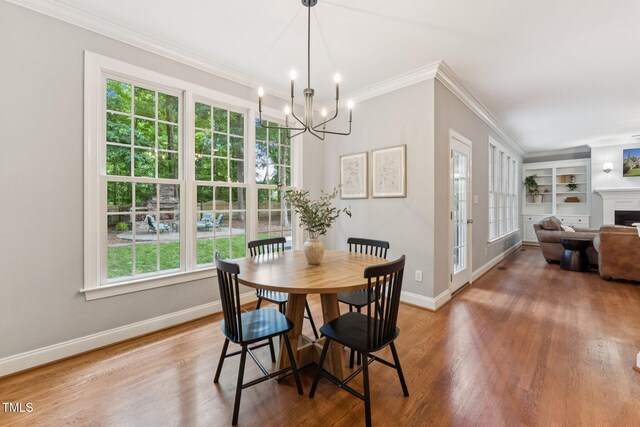 325 Wescott Ridge Dr, Holly Springs, NC 27540 - dining room with a chandelier, crown molding, wood finished floors, built in shelves, and a fireplace