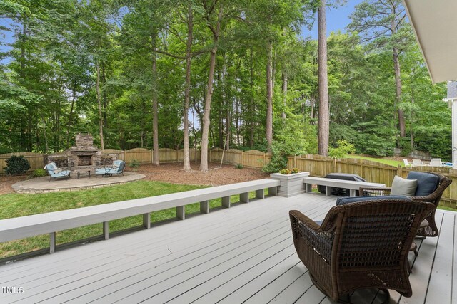 325 Wescott Ridge Dr, Holly Springs, NC 27540 - wooden deck featuring an outdoor stone fireplace, a fenced backyard, view of scattered trees, and a patio
