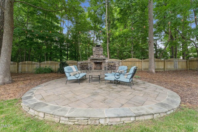 325 Wescott Ridge Dr, Holly Springs, NC 27540 - fenced backyard featuring an outdoor stone fireplace, a patio, and view of wooded area