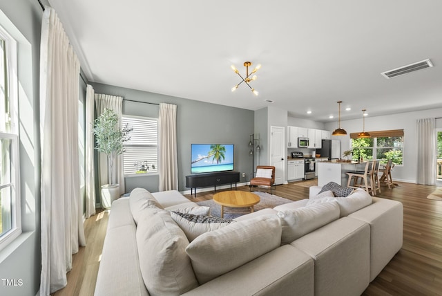 living area featuring light wood-type flooring, a chandelier, and recessed lighting