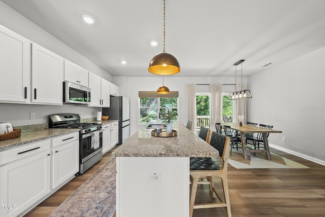 kitchen featuring appliances with stainless steel finishes, a sink, a kitchen bar, recessed lighting, and dark wood finished floors