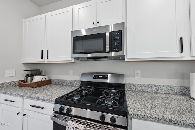 kitchen featuring appliances with stainless steel finishes, white cabinetry, and light stone counters