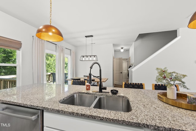 kitchen featuring a sink, decorative light fixtures, light stone countertops, and white cabinets
