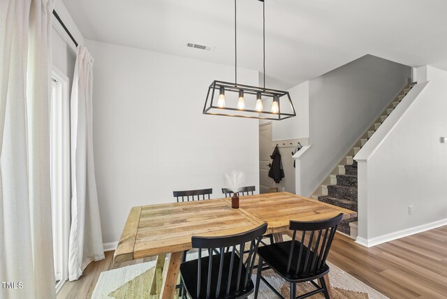 dining area featuring stairway, light wood-style floors, and baseboards