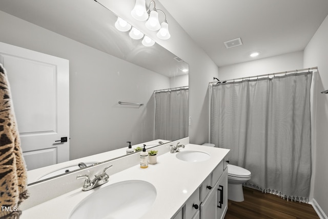 bathroom with toilet, wood finished floors, double vanity, and a shower with curtain