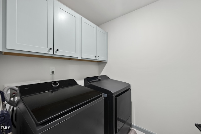 washroom with cabinet space, washing machine and dryer, and baseboards