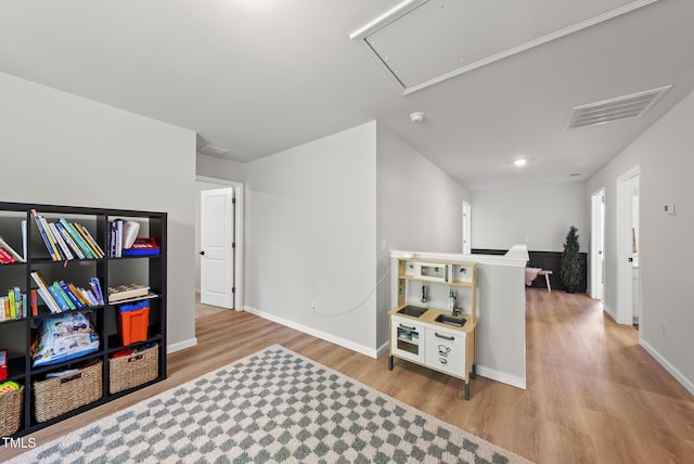 recreation room with attic access, wood finished floors, and baseboards