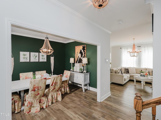 dining space with a chandelier, ornamental molding, wood finished floors, and baseboards