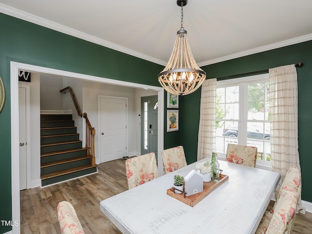 dining space featuring wood finished floors, stairs, a chandelier, ornamental molding, and baseboards