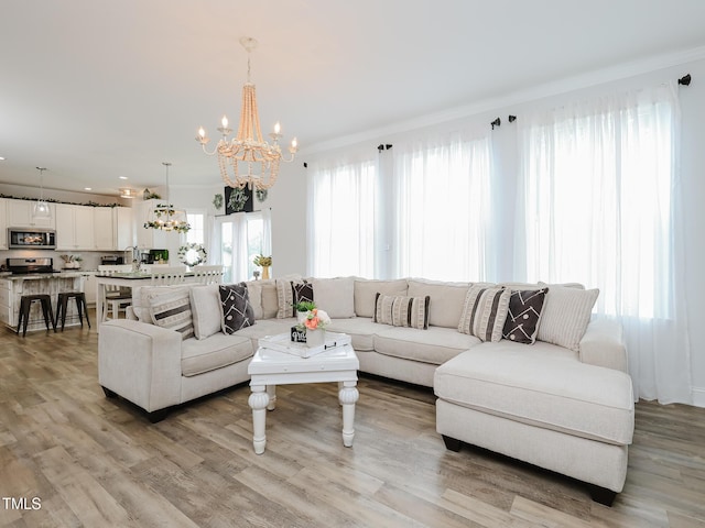 living room featuring a chandelier, light wood-type flooring, and crown molding