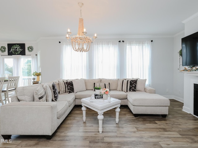 living room featuring a chandelier, crown molding, wood finished floors, baseboards, and a fireplace