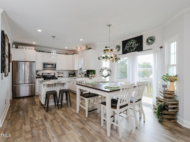 dining space with ornamental molding, wood finished floors, baseboards, a chandelier, and recessed lighting