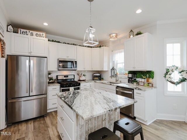 kitchen with appliances with stainless steel finishes, a sink, tasteful backsplash, ornamental molding, and light stone countertops