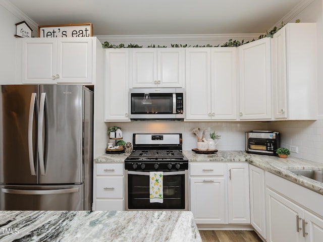 kitchen with stainless steel appliances, white cabinets, tasteful backsplash, light stone counters, and ornamental molding