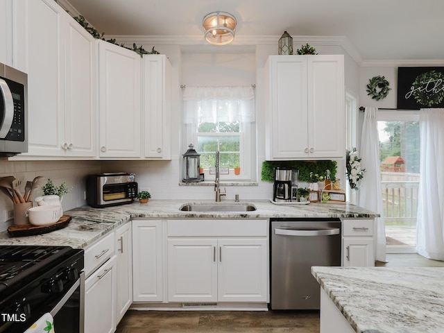 kitchen with stainless steel appliances, a sink, ornamental molding, white cabinets, and light stone countertops