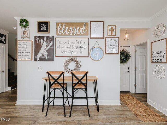 dining room with crown molding, wood finished floors, stairway, and baseboards