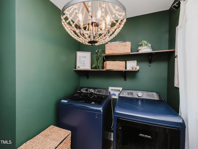 laundry room featuring washing machine and clothes dryer and a chandelier