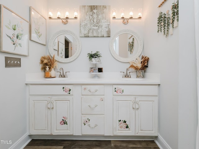 bathroom with double vanity, baseboards, and wood finished floors