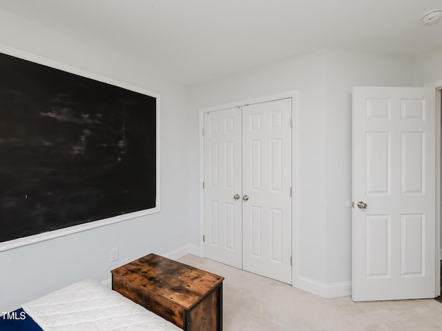 unfurnished bedroom featuring light carpet, a closet, and baseboards