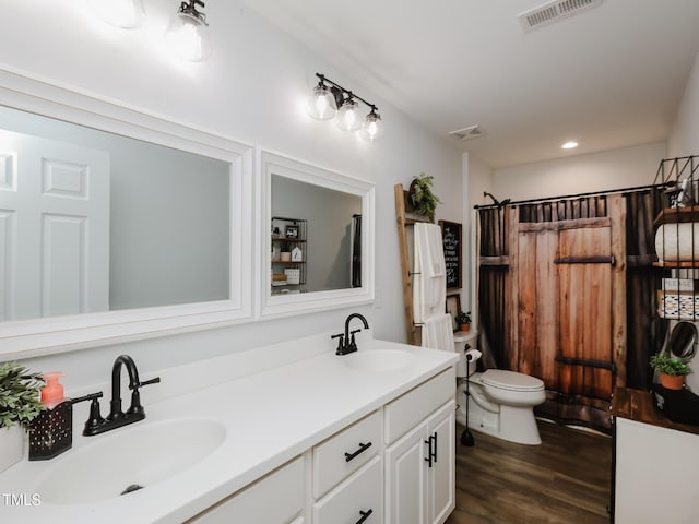 bathroom with toilet, wood finished floors, double vanity, a shower with curtain, and recessed lighting