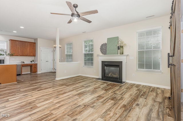 12340 Tetons Ct, Durham, NC 27703 - unfurnished living room with light wood-style floors, a glass covered fireplace, recessed lighting, and ceiling fan