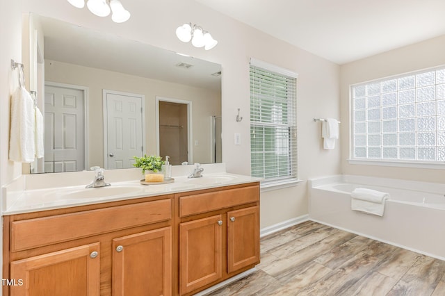 12340 Tetons Ct, Durham, NC 27703 - bathroom featuring wood finished floors, double vanity, and a garden tub
