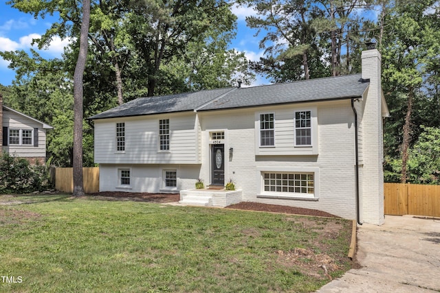 raised ranch featuring a chimney, brick siding, and roof with shingles