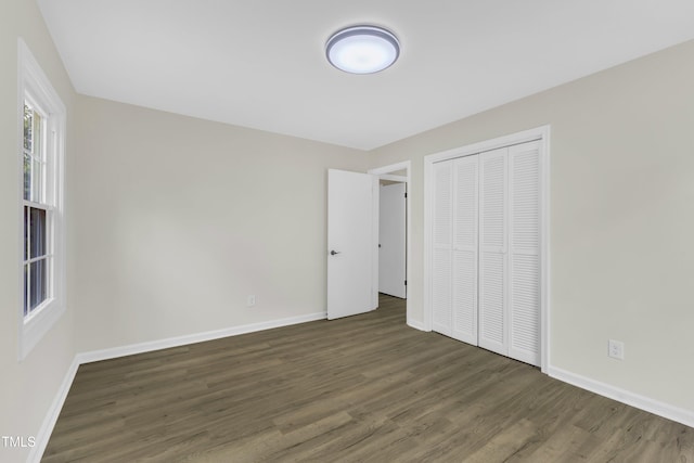 unfurnished bedroom with wood finished floors, baseboards, and a closet