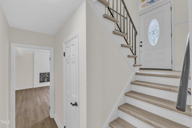 entryway with stairs, wood finished floors, and baseboards