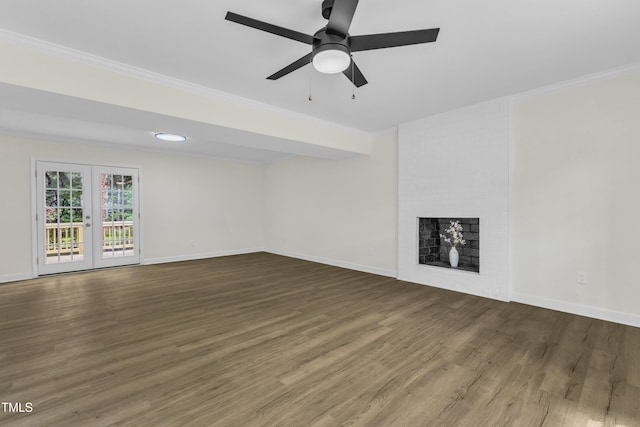 unfurnished living room featuring crown molding, wood finished floors, a brick fireplace, baseboards, and french doors