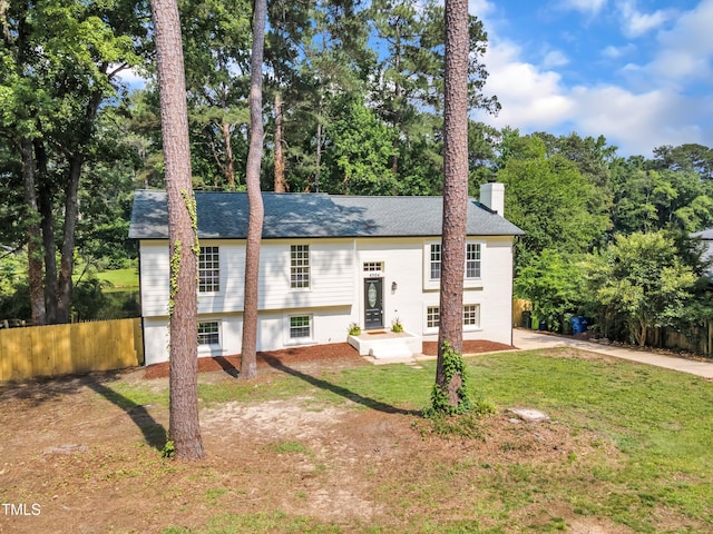 split foyer home featuring a chimney, view of wooded area, and a shingled roof