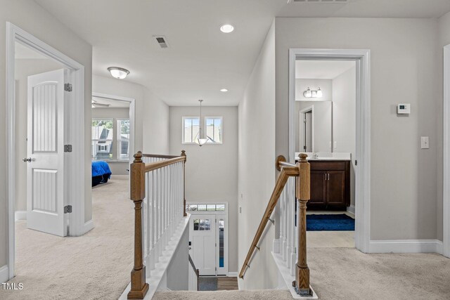 hall featuring an upstairs landing, carpet, baseboards, and recessed lighting