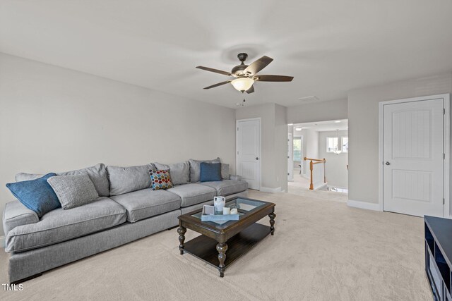 living room with baseboards, ceiling fan, and light carpet