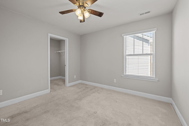 unfurnished bedroom with light colored carpet, a spacious closet, baseboards, and a closet