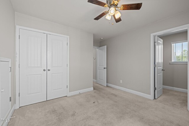 unfurnished bedroom featuring carpet, a closet, baseboards, and a ceiling fan