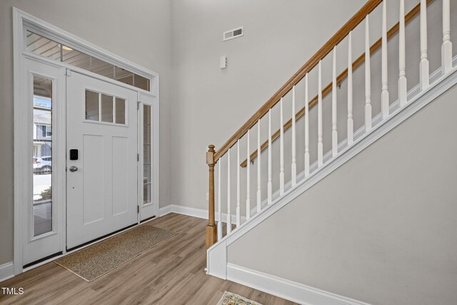 foyer with baseboards, wood finished floors, stairs, and a high ceiling